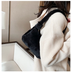 Détail de la texture douce du sac à bandoulière en fausse fourrure noire sur le modèle