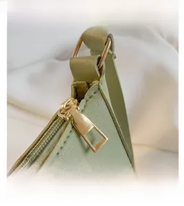 Detailed macro view of gold metal zipper and stitching on the light green leather handbag
