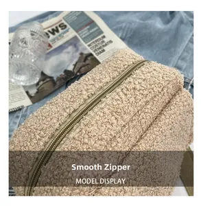 Détail macro de la fermeture éclair en métal doré clair sur le sac en polaire beige