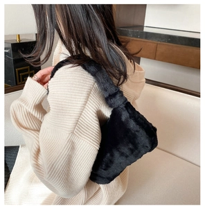 Détail d'un sac à bandoulière en peluche noire porté avec un pull en maille beige