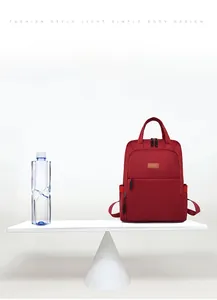 Ultralight red oxford backpack weighing only 0.42kg compared to a water bottle on a scale