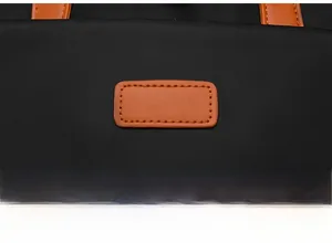 Detail eines wasserdichten Oxford-Rucksacks mit orangefarbenem Ledergriff und Kontrast-Patch