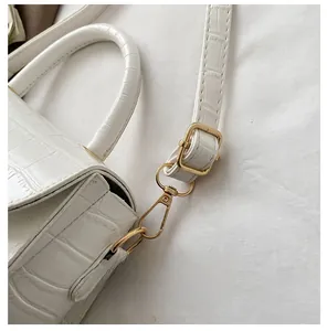 Detail of white crocodile pattern shoulder bag with gold metal hooks and romantic text