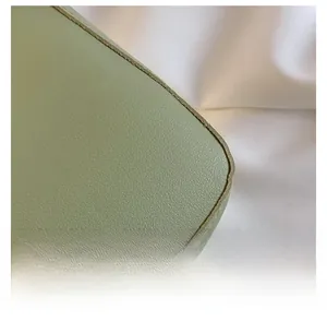 Close-up of light green lychee texture leather bag edges with fine stitching details
