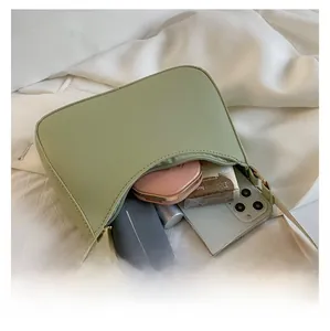 Internal storage view of mini sage green shoulder bag showing mobile phone and makeup essentials