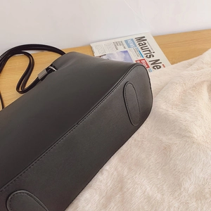 Sac cabas classique en cuir noir avec texture grainée et base cousue sur un bureau
