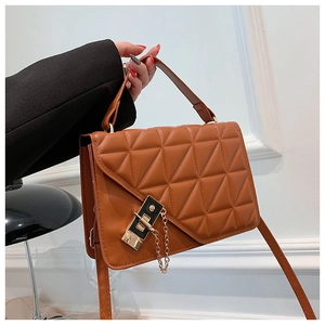 Detail showing brown quilted crossbody bag with golden lock and chain decoration