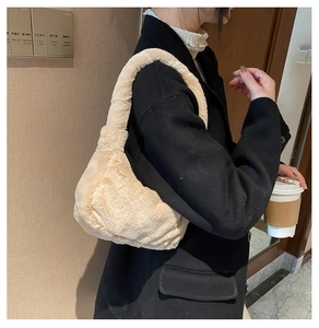 Détail d'un sac à bandoulière en fausse fourrure crème porté par un mannequin en intérieur