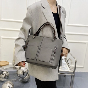 Gray faux leather tote bag with dual front zipper pockets and brown contrast handles