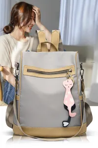 Detail of grey water-resistant nylon backpack with brown leather accents and cat charm