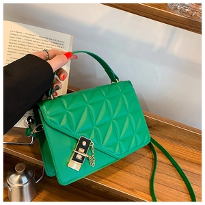 Close-up of a green quilted crossbody bag with golden chain detail on wooden steps
