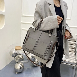 Grey frosted leather tote bag with double pockets and brown straps worn by a model