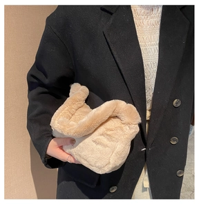 Gros plan du sac à main pelucheux en fausse fourrure beige porté sur un manteau noir
