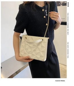 Detail of white geometric quilted tote bag with gold chain strap on female model