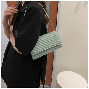 Detail of mint green quilted baguette bag with gold hardware and slim shoulder strap