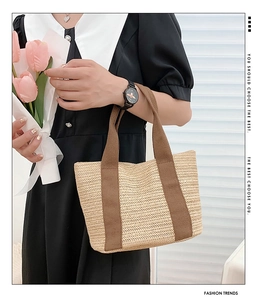 Detail of hand-woven straw tote bag with V-shaped texture and brown canvas handles
