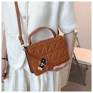 Brown quilted leather crossbody bag with gold buckle shown on person in modern interior