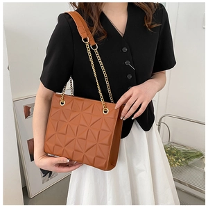 Detail of a brown leather tote bag with quilted geometric patterns and gold chain strap