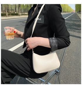Chic beige leather hobo shoulder bag with adjustable strap worn on an outdoor commute