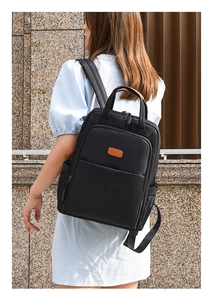 Outdoor shot of a black Oxford fabric backpack with leather details on a female model