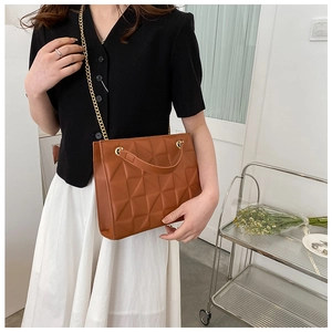 Detail of brown quilted tote bag with geometric pattern and gold chain strap