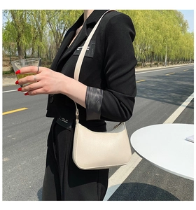 Chic cream-white leather Hobo bag worn by model in a stylish outdoor setting