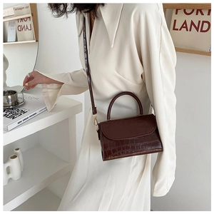 Close-up of dark brown crocodile embossed leather handbag with elegant gold hardware