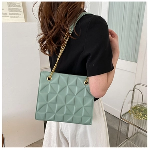 Detail of mint green tote bag featuring 3D geometric texture and gold chain strap