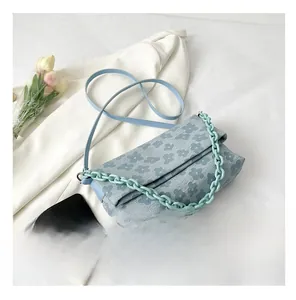 Détail de la texture florale sur un petit sac bleu avec chaîne en résine et bandoulière
