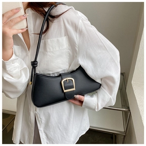 Detail of black crescent underarm bag featuring a wide strap with decorative knot and buckle