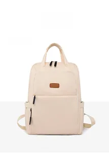 Detail view of a minimalist beige oxford backpack with brown label and side pockets