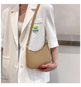 Chic light brown crescent underarm bag shown on a model wearing a white blazer