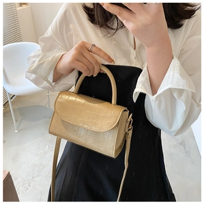 Detail of light beige crocodile embossed square bag with adjustable shoulder strap