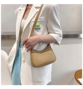 Close-up of minimalist beige PU hobo bag worn by a model in a stylish white suit