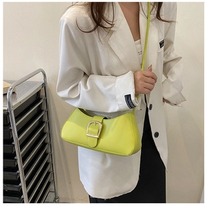 Detail of neon green shoulder bag with gold square buckle worn with white blazer