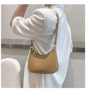 Close-up of a khaki faux leather Hobo shoulder bag worn with a white blazer