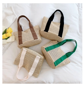 Detailed view of four straw woven tote bags in brown, black, beige, and green colors