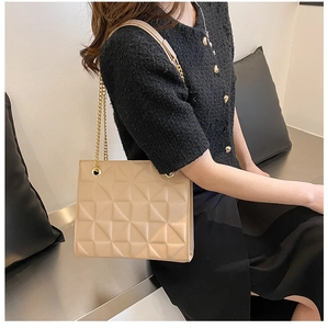 Detail of beige geometric quilted shoulder bag with gold chain strap and leather padding
