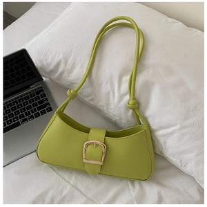 Detailed shot of lime green baguette bag with large gold buckle on white bedding