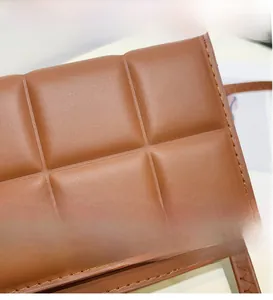 Close-up detail of brown quilted PU leather with fine stitching on the small square crossbody bag
