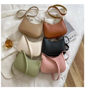 Flat lay of six colorful minimalist PU leather half-moon shoulder bags on a white sheet