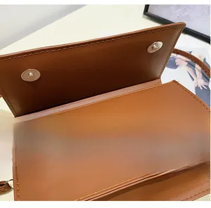 Detail showing dual magnetic snap closures and fine stitching on a brown leather bag