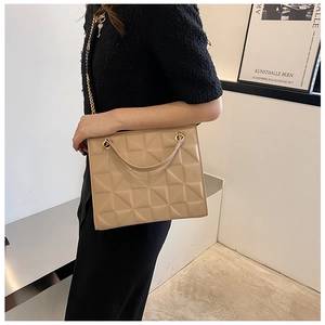 Detail of beige quilted tote bag with gold chain strap and elegant texture
