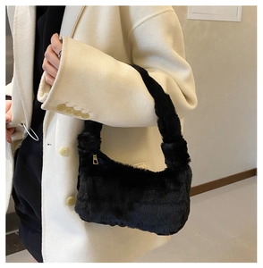 Détail du sac à bandoulière en peluche noire avec fermeture éclair dorée sur manteau