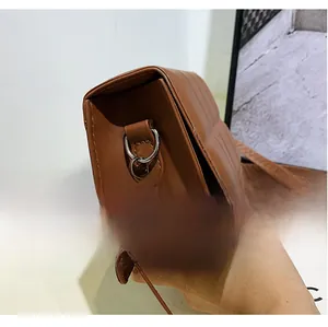 Detail view of brown crossbody bag showing vertical stitched texture and silver metal rings