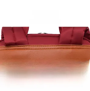 Close-up of precise stitching on red nylon backpack with brown leather trim detail