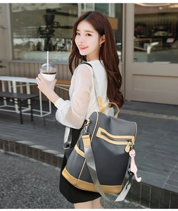Detail view of water-resistant nylon backpack showing anti-theft back zipper and cat charm