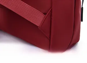 Macro shot of reinforced triangle stitching on the dark red nylon backpack shoulder straps