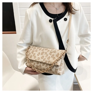 Détail d'un sac bandoulière en toile florale avec bandoulière chaîne et motif vintage