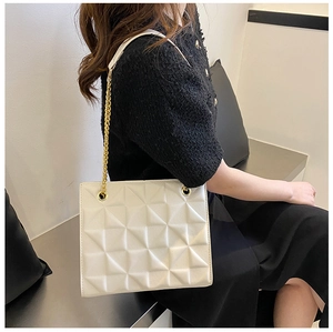 Detail view of a white shoulder bag with 3D geometric relief and a gold chain strap